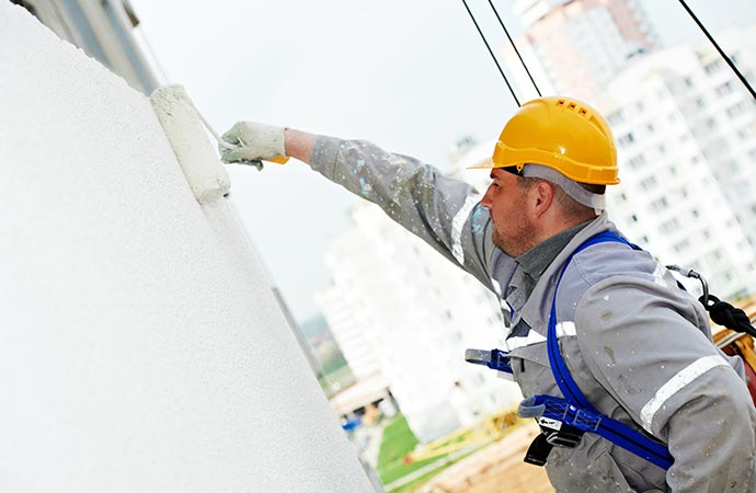 A worker painting a commercial building.