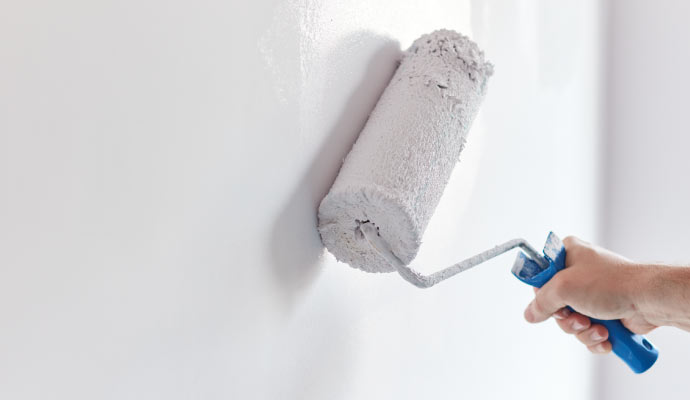 a person is applying white paint on the wall using a paint roller
