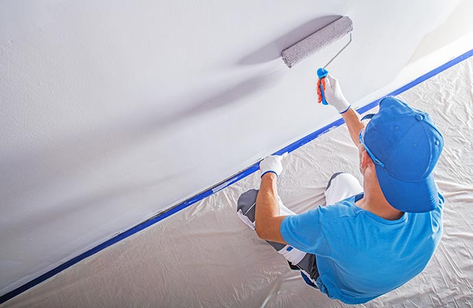 Painter working on painting the interior of a retail store.